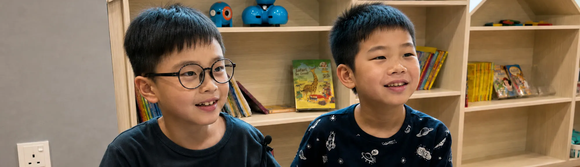 Two TITAN students at their desk in a classroom lined with books