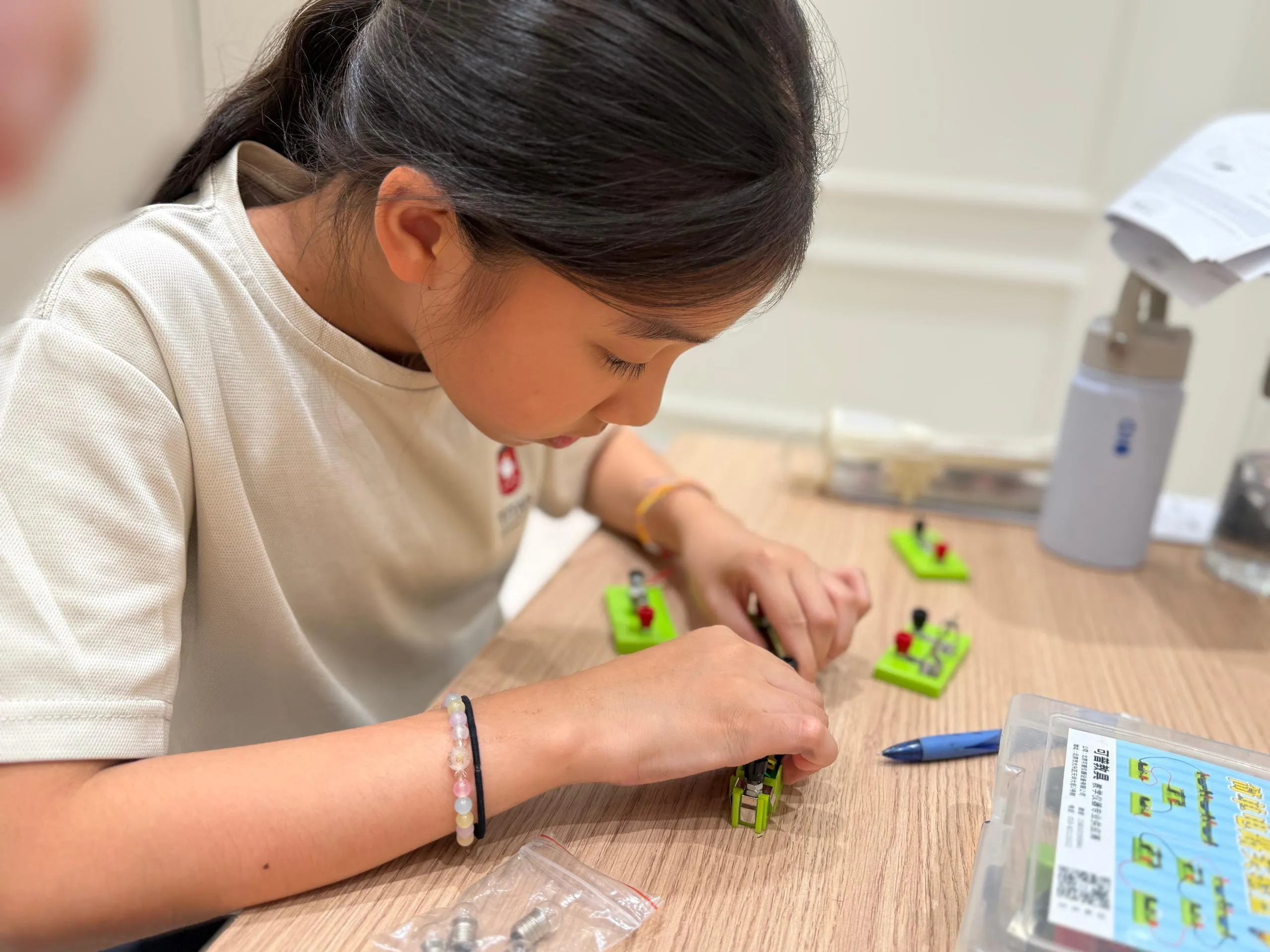 A TITAN student wiring a small electrical circuit from components at her desk